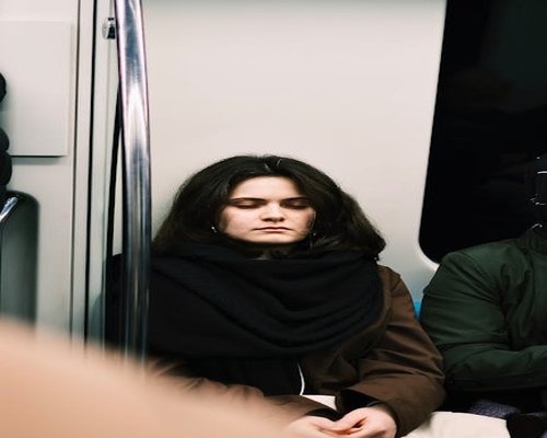 A person resting their eyes while sitting on a train